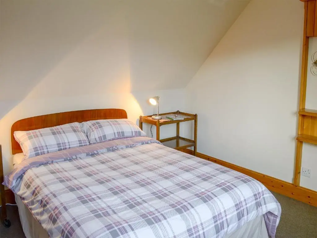 a bedroom with a bed with a checkered blanket at Lower Brae in Achnahanat