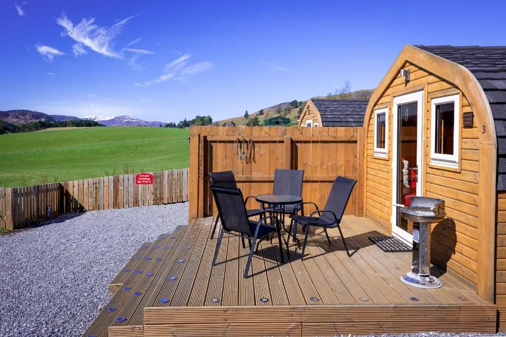 a wooden deck with a table and chairs on it at Tigh an Each B&B & Laggan Glamping in Newtonmore