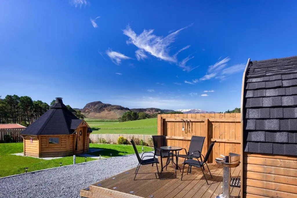 a deck with chairs and a small wooden house at Tigh an Each B&B & Laggan Glamping in Newtonmore