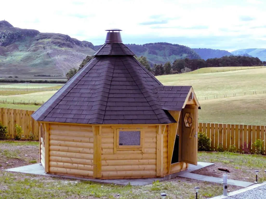a small wooden cabin with a black roof at Tigh an Each B&B & Laggan Glamping in Newtonmore