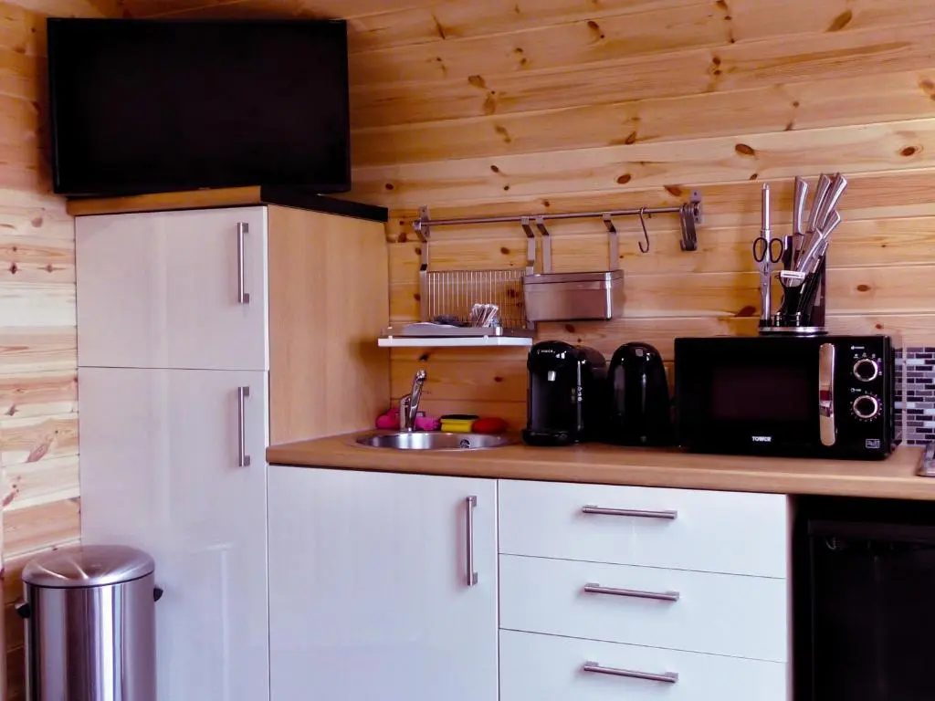 a kitchen with white cabinets and a black microwave at Tigh an Each B&B & Laggan Glamping in Newtonmore