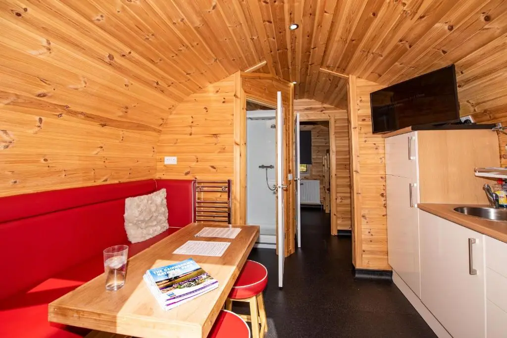a living room with a red couch and a table at Tigh an Each B&B & Laggan Glamping in Newtonmore