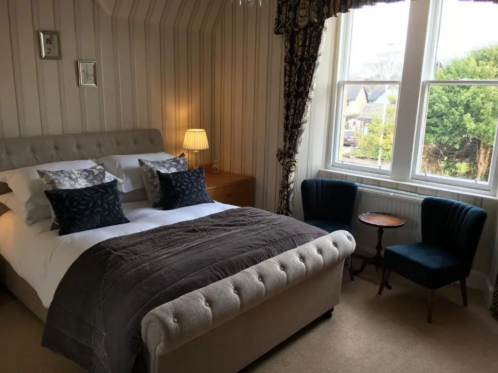 a bedroom with a bed and a chair and a window at Ballifeary House in Inverness