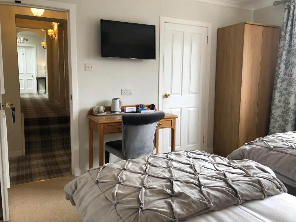 a hotel room with a desk and a bed at Ballifeary House in Inverness