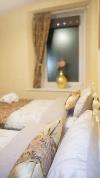 a bedroom with two beds with pillows and a window at Cozy Central Apartment in Inverness