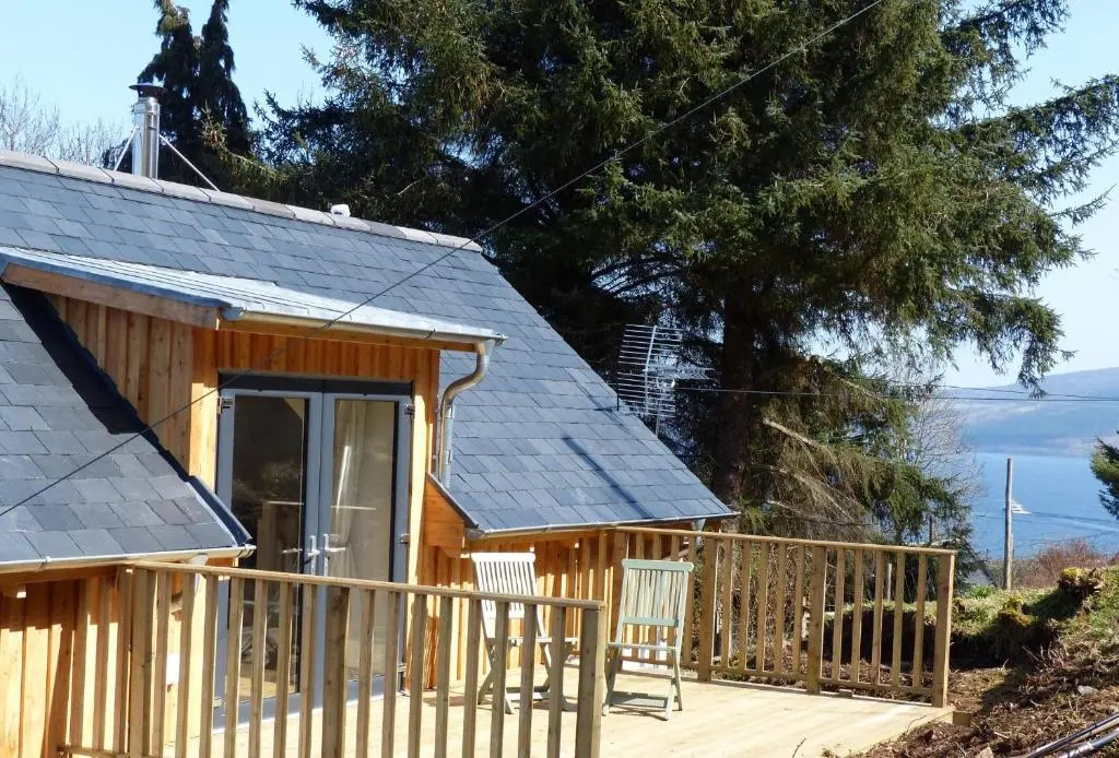 a log cabin with a porch and a deck at Urquhart Bay Croft in Drumnadrochit
