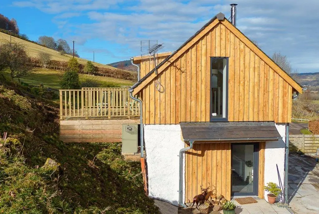 a small house on a hill with a balcony at Urquhart Bay Croft in Drumnadrochit