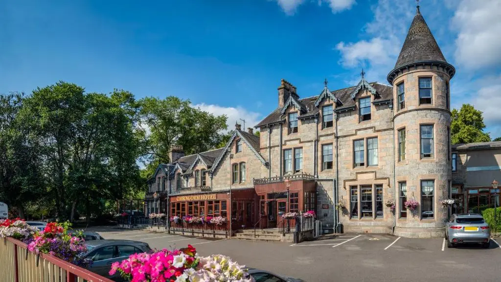 a large stone building with a turret on a street at Cairngorm Hotel in Aviemore