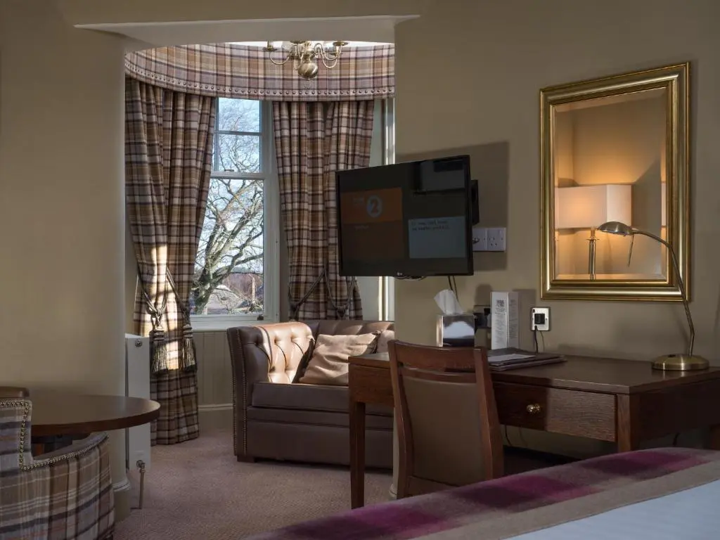 a living room with a couch and a desk with a computer at Cairngorm Hotel in Aviemore
