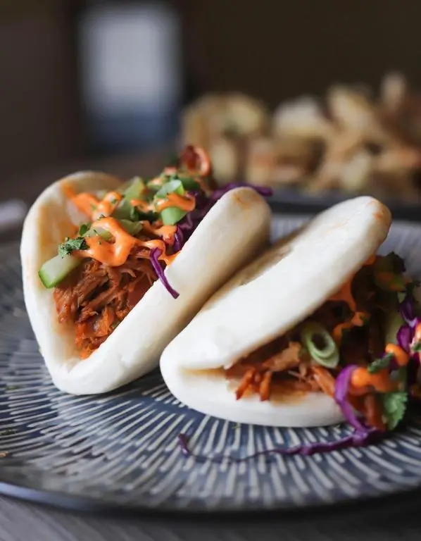 two hot dogs sitting on a plate with toppings at Ardennan House Hotel in Inverurie
