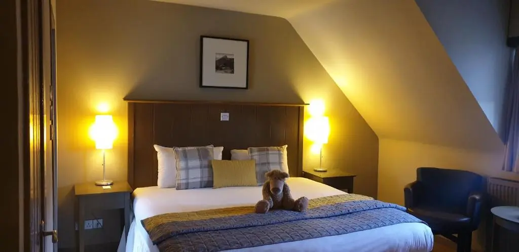 a teddy bear sitting on a bed in a hotel room at Garth Hotel in Grantown on Spey