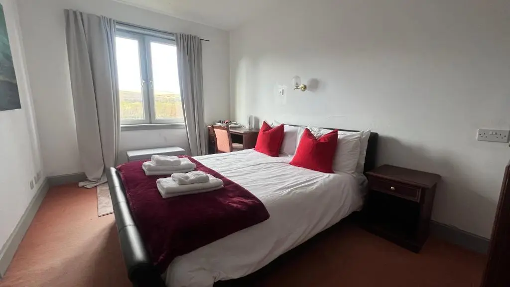 a bedroom with a large bed with red pillows at Hotel Square in Tomintoul