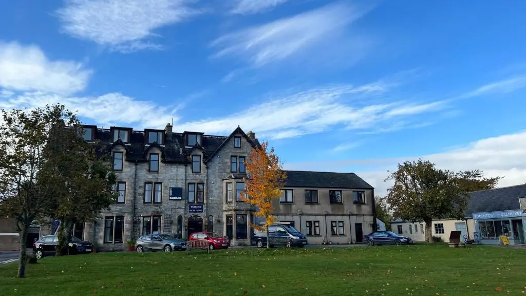a large building with cars parked in front of it at Hotel Square in Tomintoul