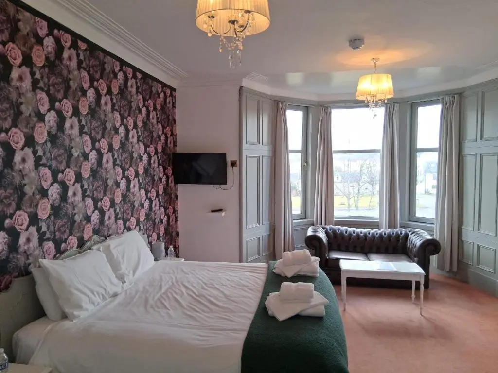 a bedroom with a bed and a wall with a wallpaper at Hotel Square in Tomintoul