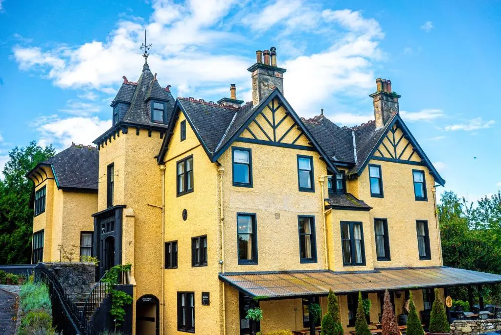 a large yellow house with a black roof at Craigellachie Hotel of Speyside in Craigellachie