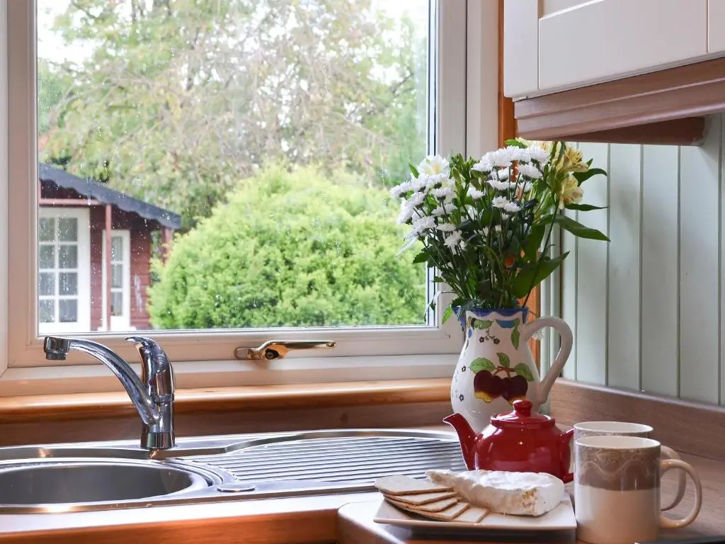 a kitchen sink with a vase of flowers in a window at Viewhill Villa in Inverness