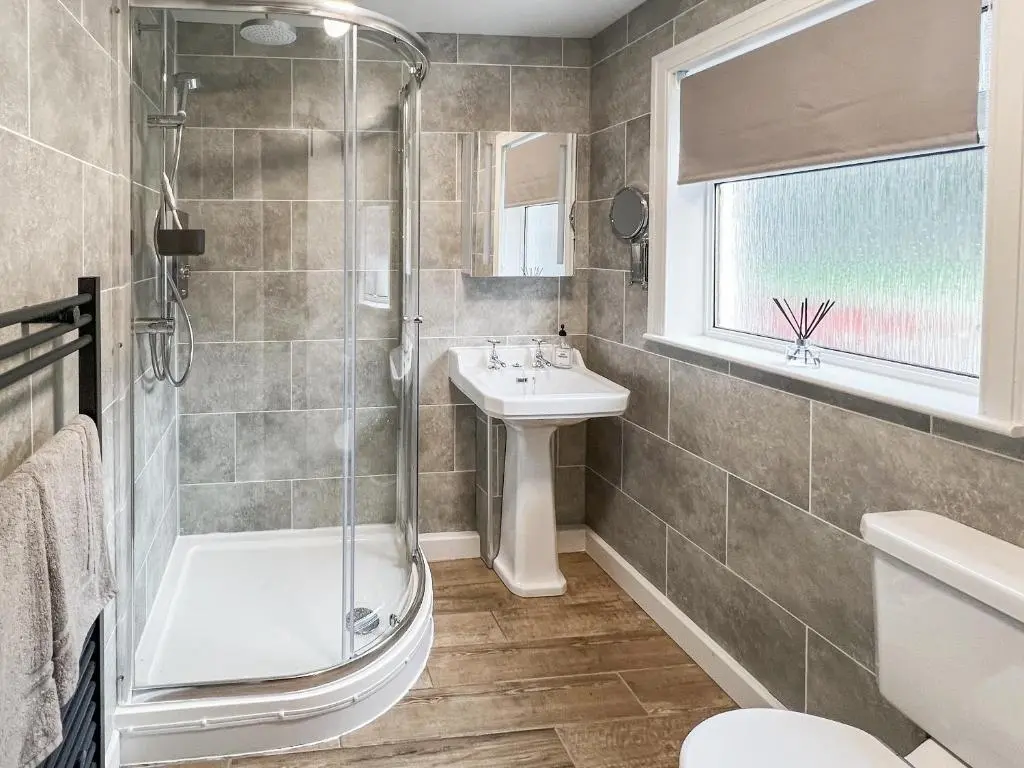 a bathroom with a shower toilet and a sink at Riverside Cottage in Drumnadrochit