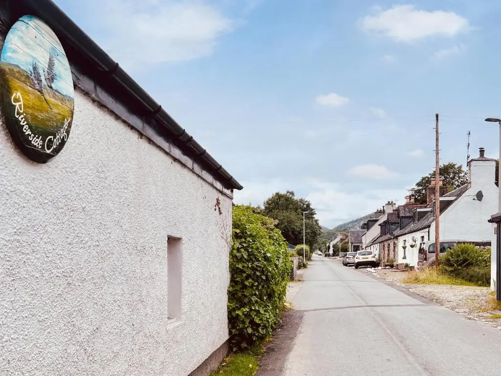 a sign on the side of a building next to a street at Riverside Cottage in Drumnadrochit