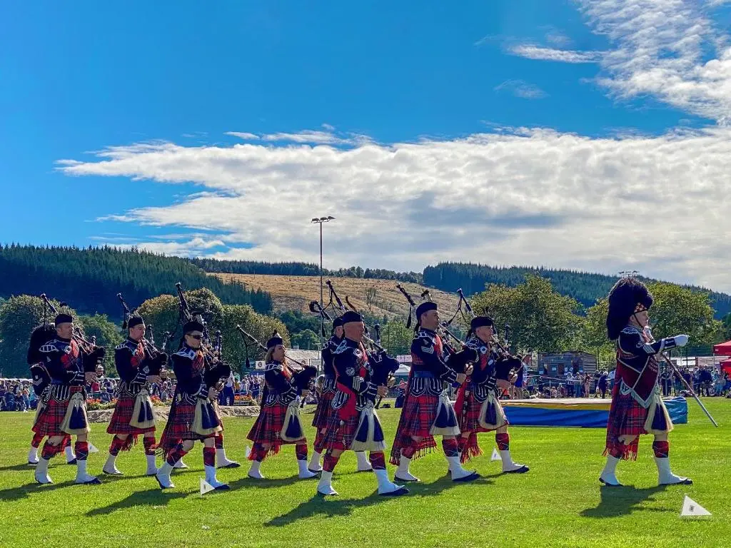 a group of people in uniform playing music in a field at Riverside Cottage in Drumnadrochit