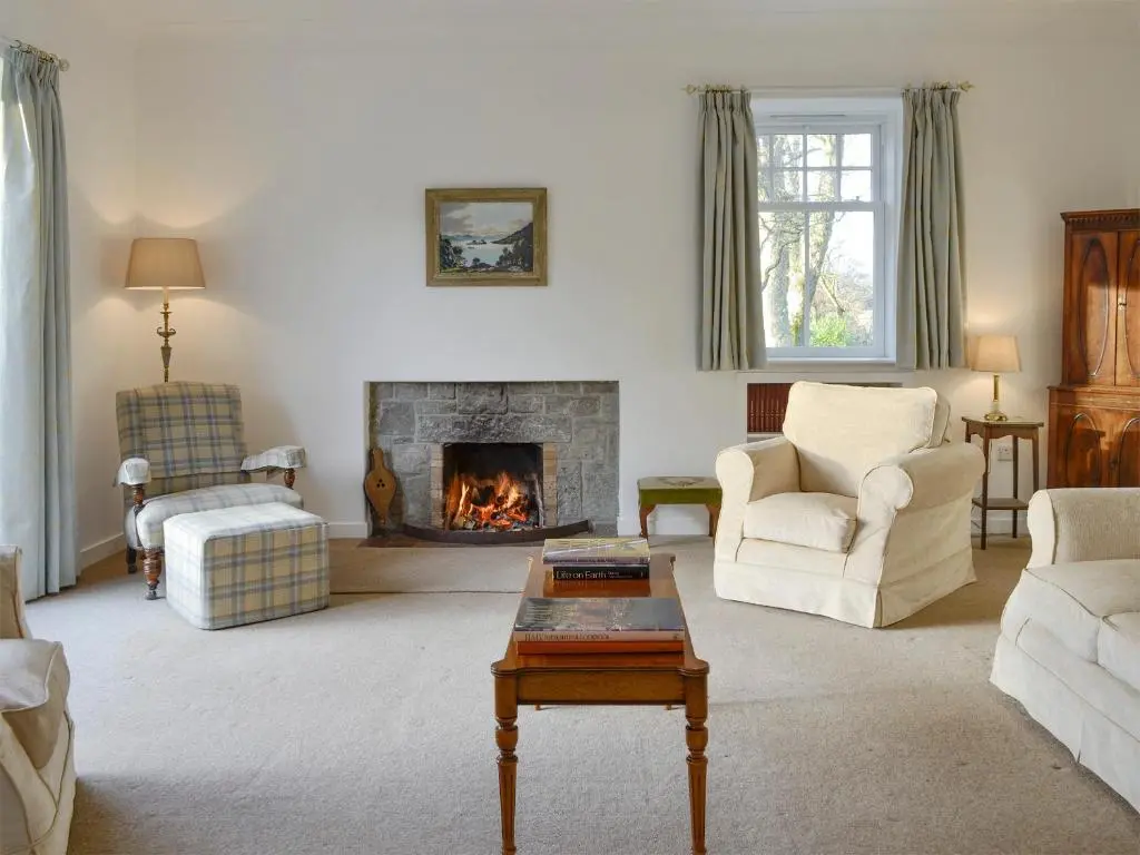 a living room with a fireplace and a couch and chairs at The Coach House in Alford