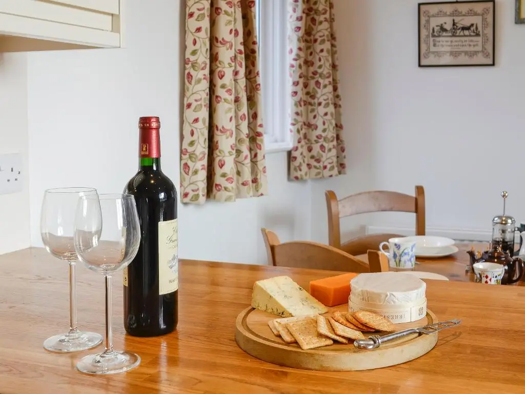 a bottle of wine and glasses on a wooden table at The Coach House in Alford