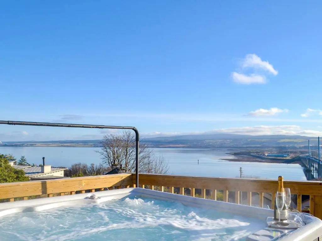 a hot tub on a balcony with a view of the water at Balnacraig in North Kessock