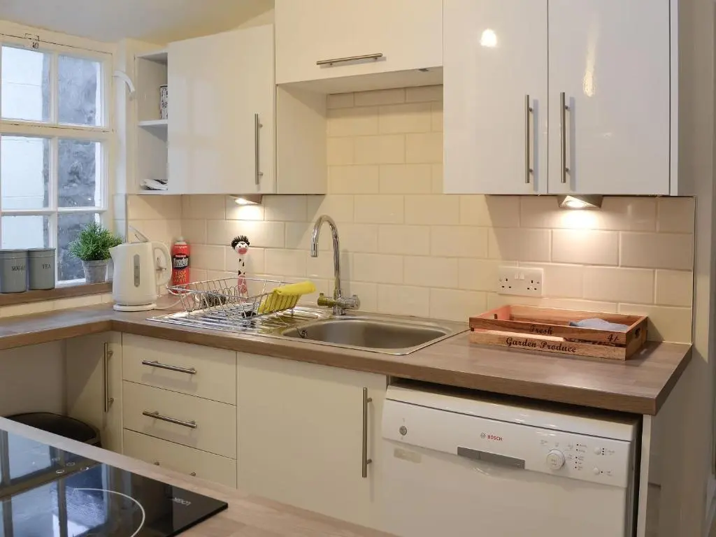 a kitchen with white cabinets and a sink at Jebel in Cullen