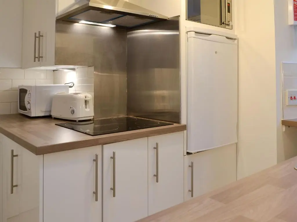 a kitchen with white cabinets and a sink and a microwave at Jebel in Cullen