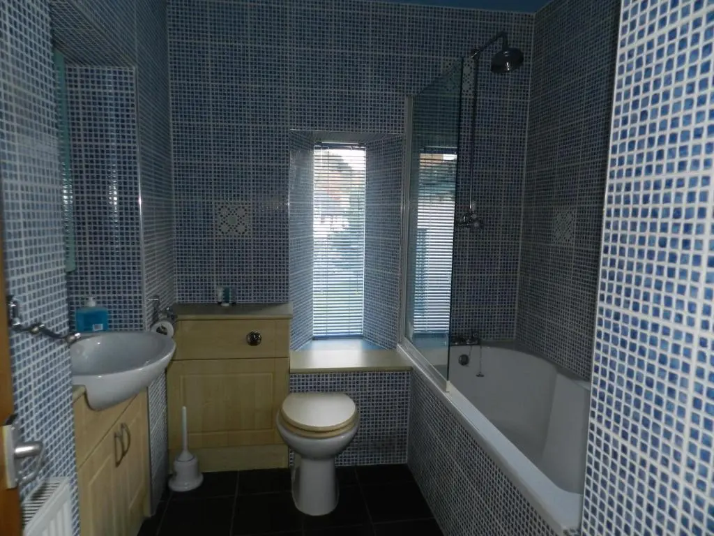 a bathroom with a toilet and a tub and a sink at Clunebeg Lodge in Drumnadrochit