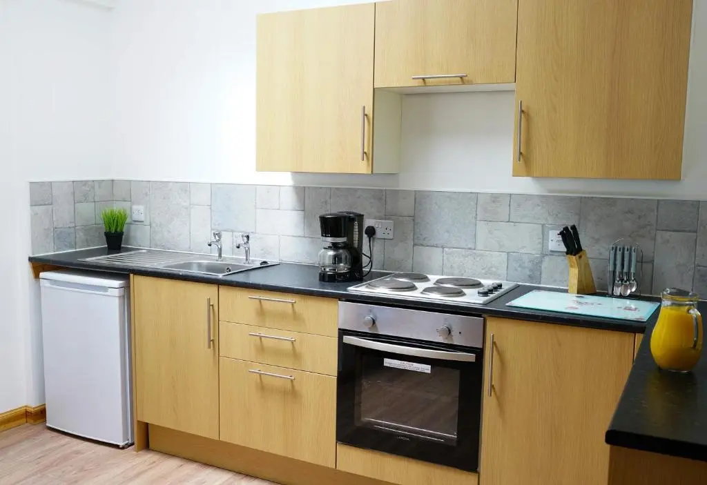 a kitchen with wooden cabinets and a stove top oven at Millburn Apartments in Inverness