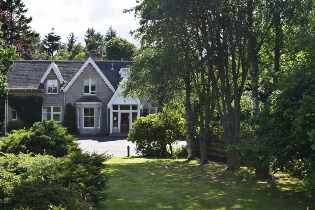 a house with a driveway and a yard with trees at No 45, Ballater in Ballater