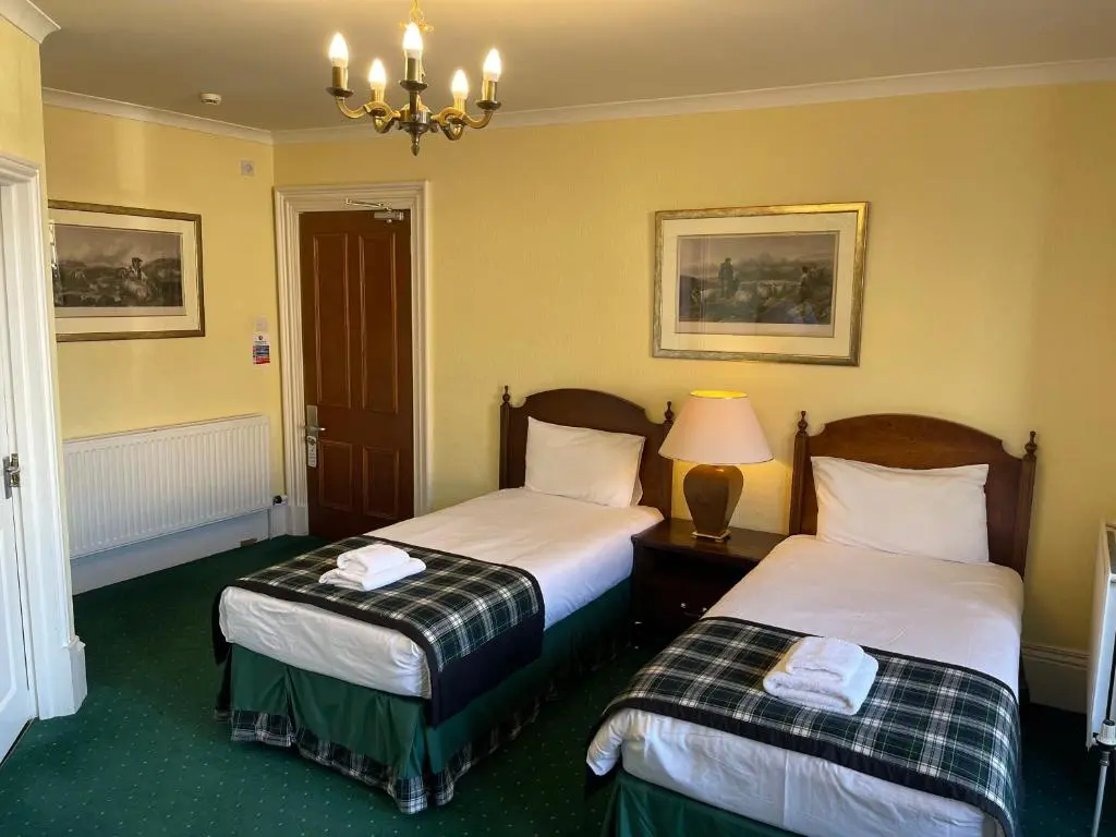 a hotel room with two beds and a lamp at Lovat Arms Hotel in Beauly