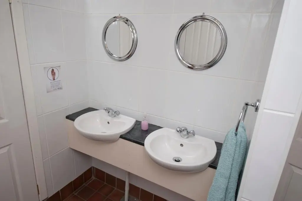 a bathroom with two sinks and two mirrors at Gulabin Lodge in Glenshee