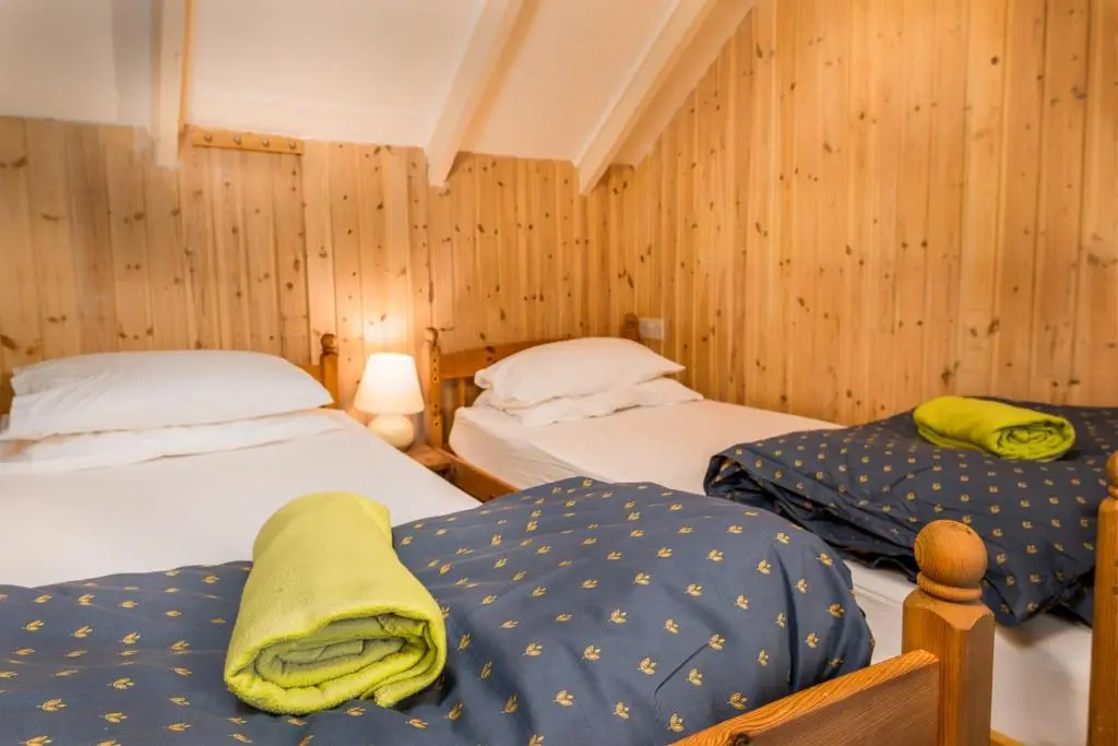 two twin beds in a room with wooden walls at Gulabin Lodge in Glenshee