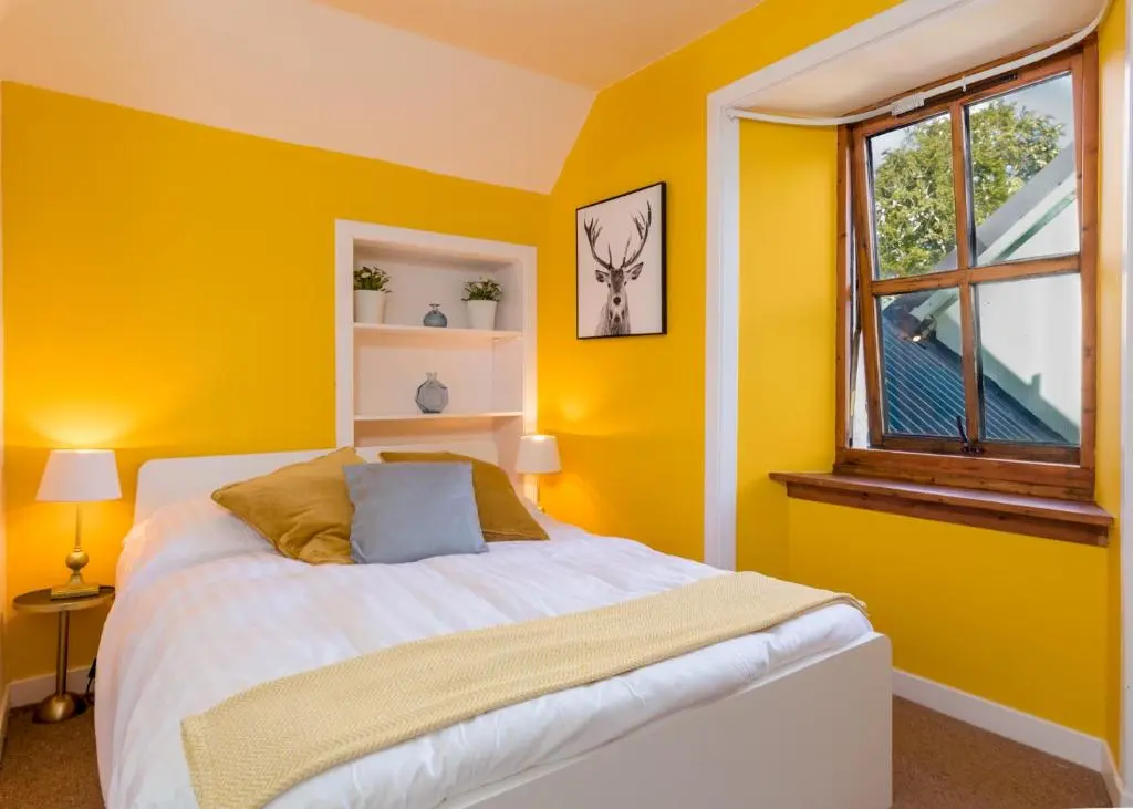 a yellow bedroom with a bed and a window at Gulabin Lodge in Glenshee