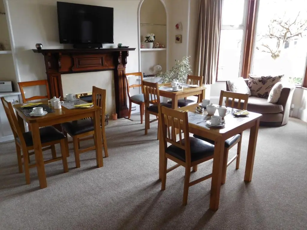 a living room with tables and chairs and a television at The Castle B&B in Inverness