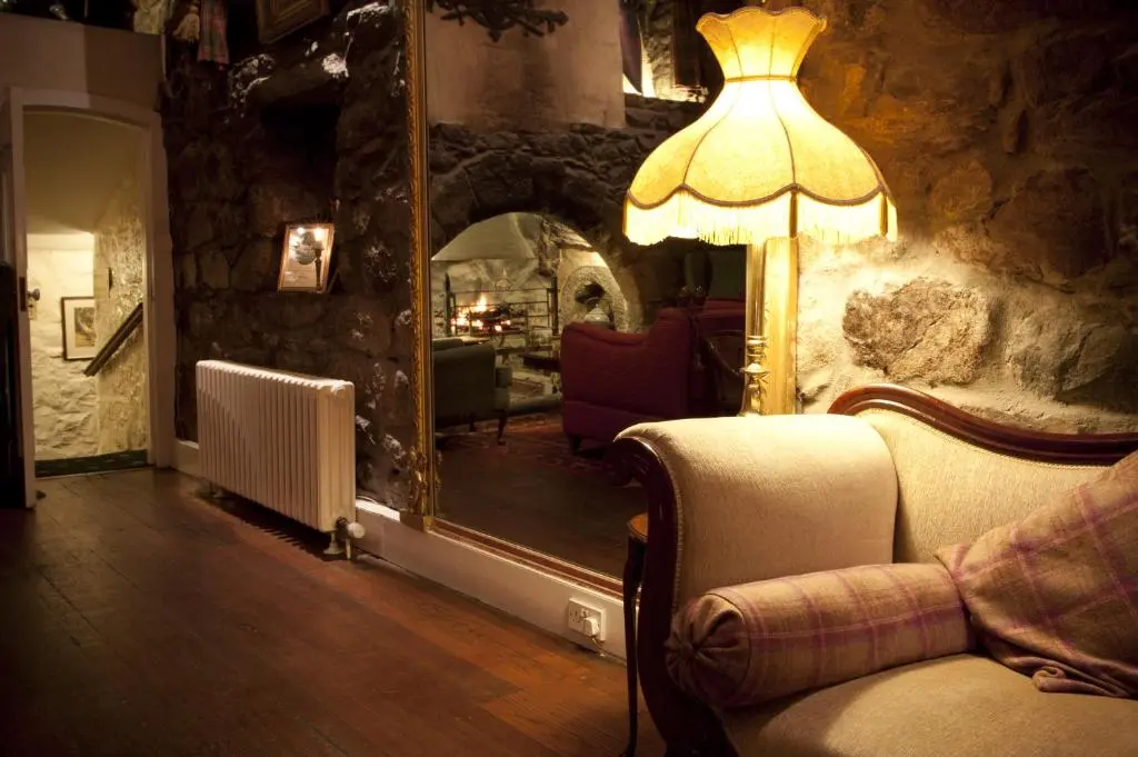 a living room with a lamp and a mirror at Maryculter House in Maryculter