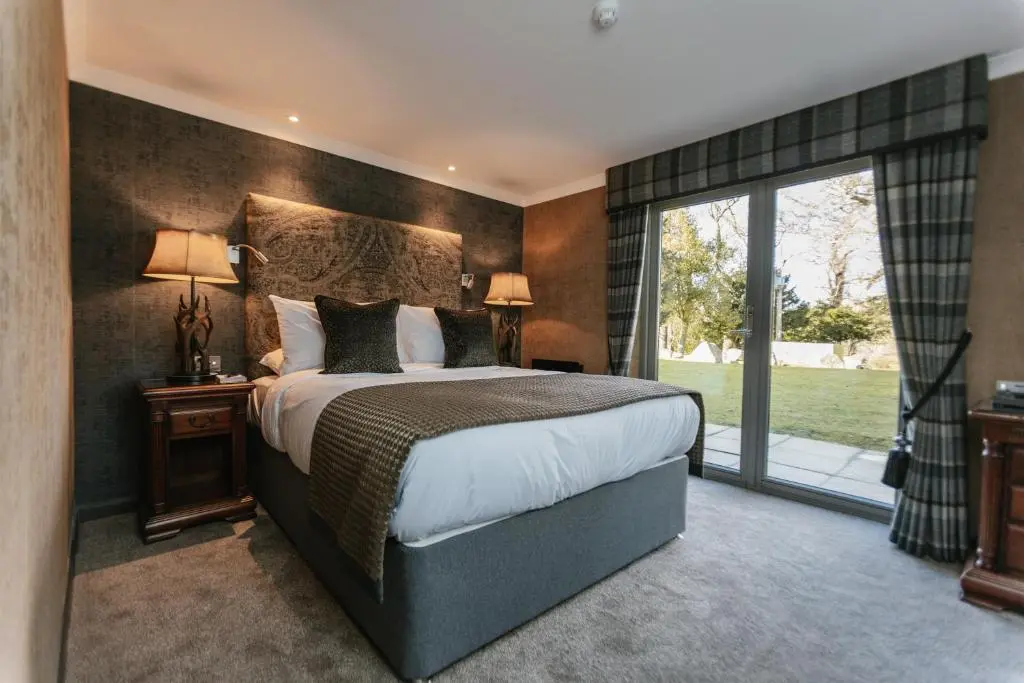 a bedroom with a large bed and a large window at Maryculter House in Maryculter
