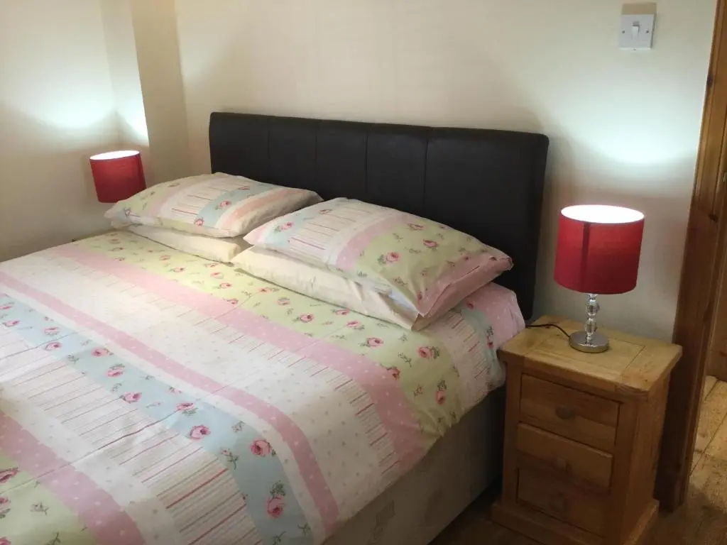 a bedroom with a bed with a red lamp on a night stand at Four-Bedroom House - Stratherrick Free Parking in Inverness