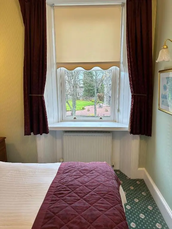 a bedroom with a bed and a large window at Ravenscourt House, Guest House in Grantown on Spey