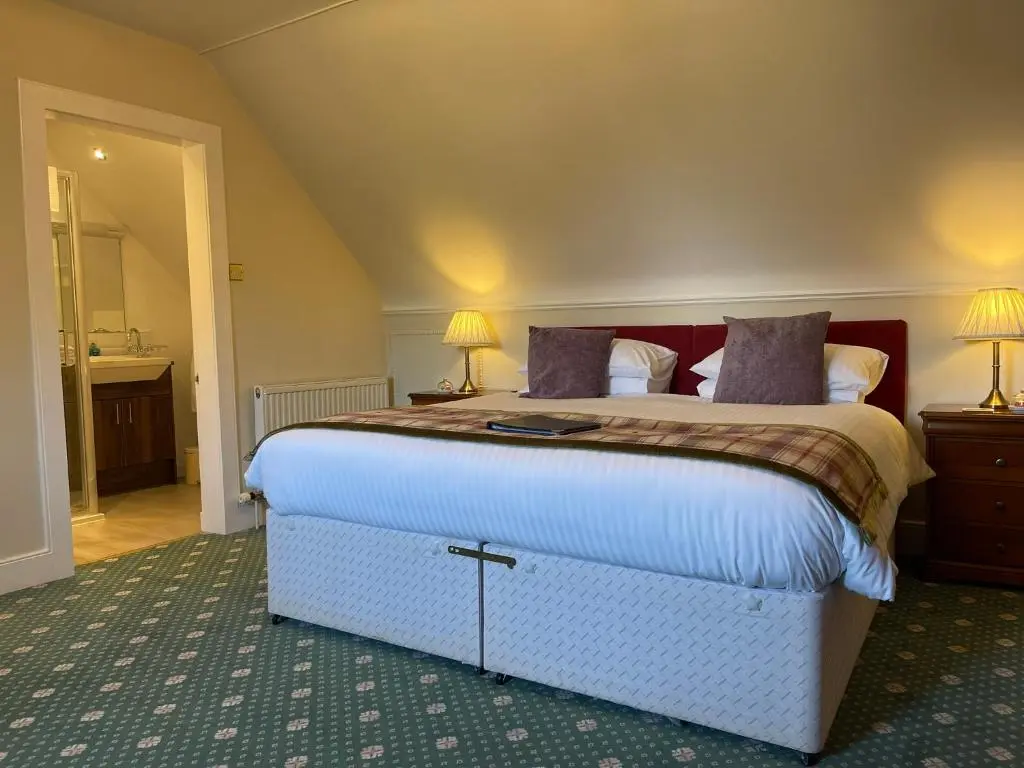 a bedroom with a large bed and two lamps at Ravenscourt House, Guest House in Grantown on Spey