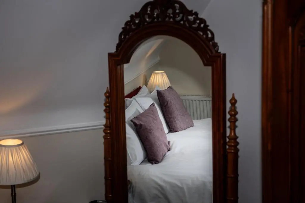 a bedroom with a bed with a large mirror at Ravenscourt House, Guest House in Grantown on Spey