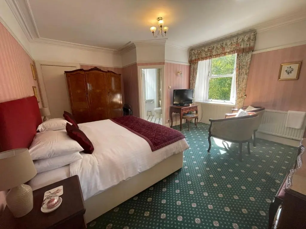 a bedroom with a bed and a desk and a television at Ravenscourt House, Guest House in Grantown on Spey