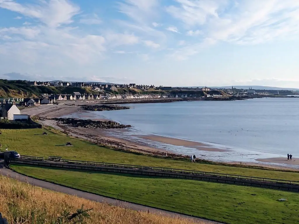 a beach with people walking on the sand and the water at Marine Hotel in Buckie