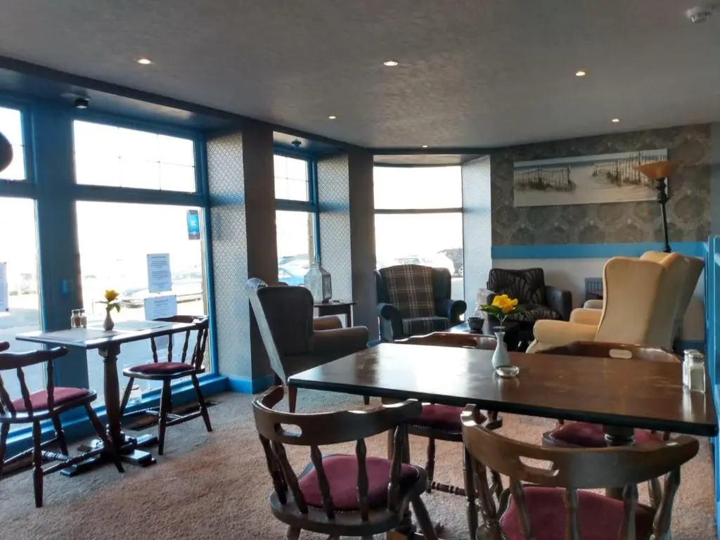 a dining room with tables and chairs and windows at Marine Hotel in Buckie