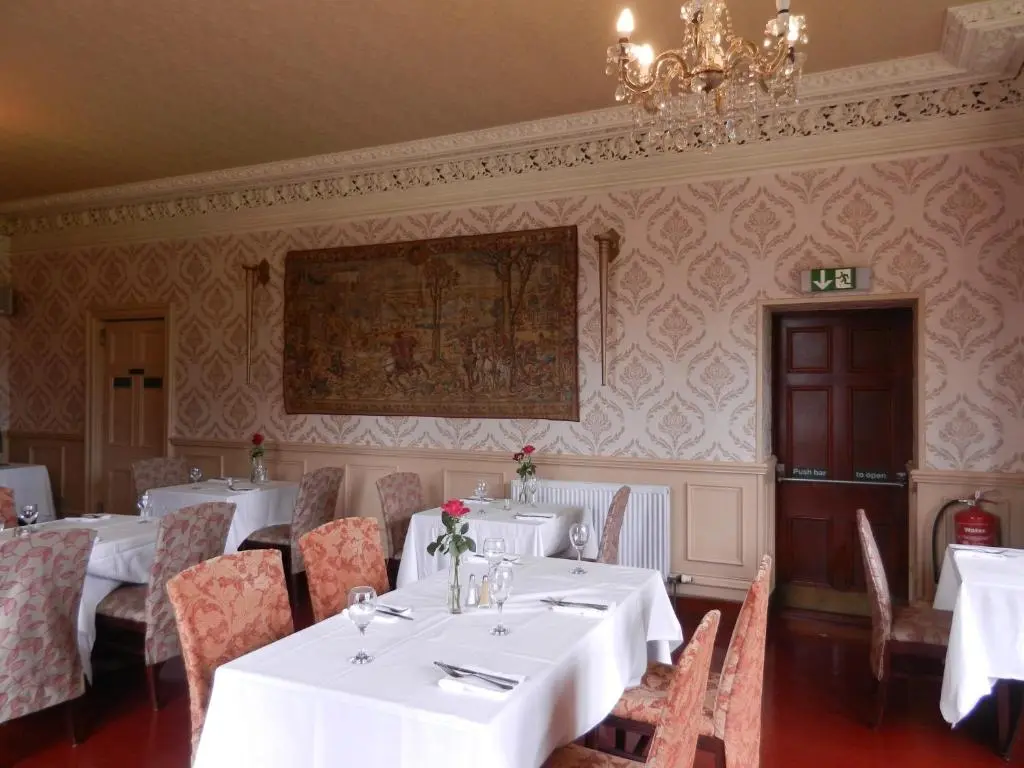 a dining room with white tables and chairs and a chandelier at Mansfield Castle Hotel in Tain