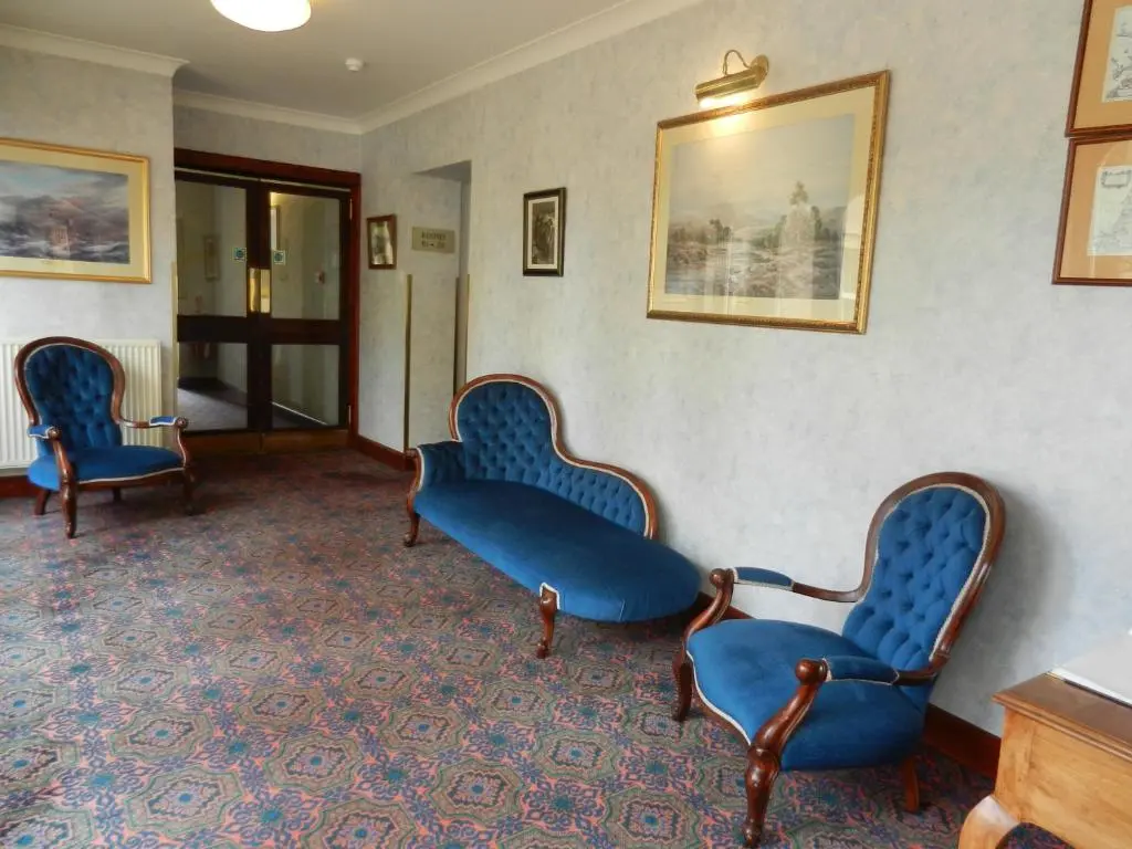a waiting room with blue chairs and paintings on the wall at Morangie Hotel Tain in Tain