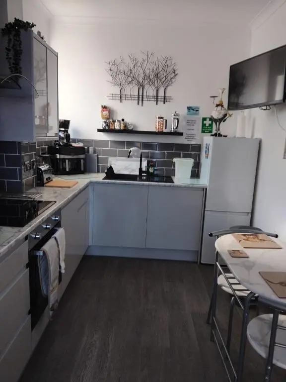 a kitchen with white appliances and a table in it at Fairfield Townhouse Guest House in Inverness