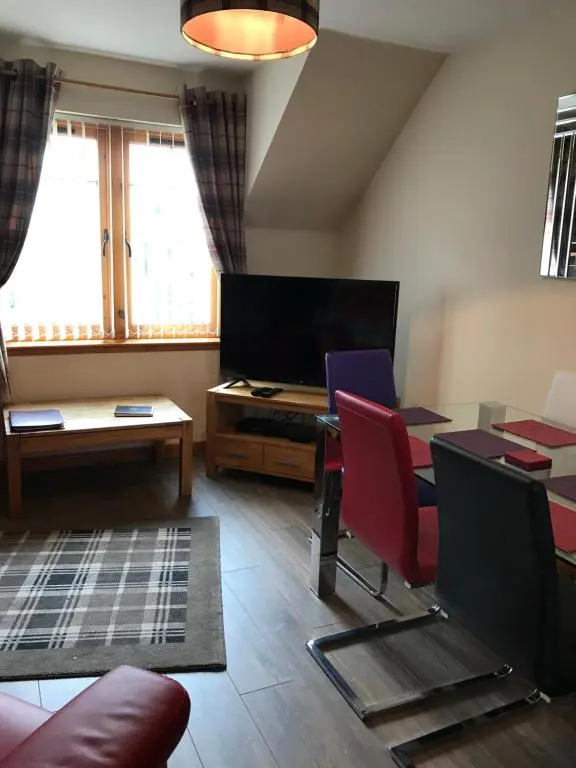 a living room with a table and chairs and a tv at Cairngorm Mountain View in Aviemore