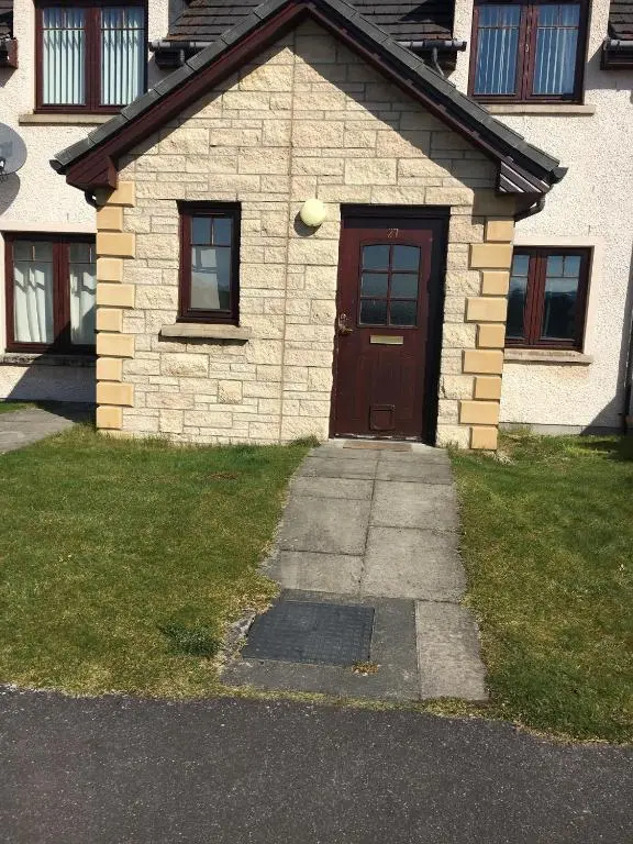 a brick house with a brown door and grass at Cairngorm Mountain View in Aviemore